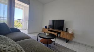 a living room with a couch and a flat screen tv at L'Échappée Bleue Sea view studio in Moule in Le Moule