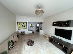 a living room with a large television and a chandelier at Cozy Beachfront 2BR in Rabat - Central & Secure in Rabat