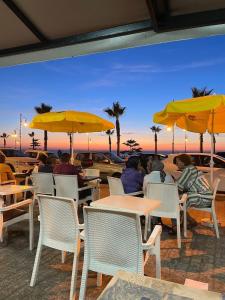 a group of people sitting at tables under yellow umbrellas at Cozy Beachfront 2BR in Rabat - Central & Secure in Rabat