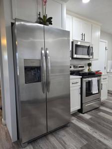 a stainless steel refrigerator in a kitchen with white cabinets at Brand new everything! Adjustable beds! Best House in Lawton +11 photos