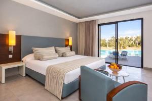 a bedroom with a bed and a view of a pool at Cesar Thalasso in Midoun +42 photos