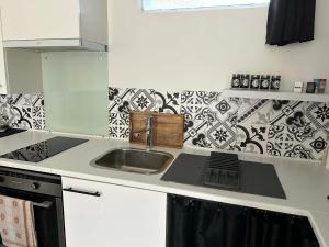 a kitchen with a sink and black and white tiles at Le studio de Louisette in Châteaudun +2 photos