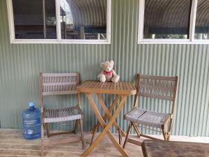 a teddy bear sitting on a table next to two chairs at Forest Gypsy Tiny Home in Barkers Vale