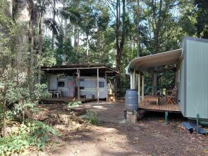 a small house with a porch and a trailer at Forest Gypsy Tiny Home in Barkers Vale