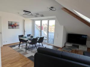 a living room with a table and chairs and a television at Rooftop Apartment in Kornwestheim