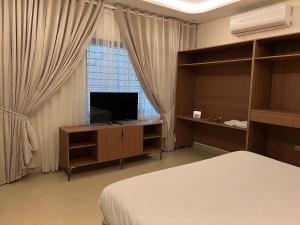 a bedroom with a bed and a television and a window at Heritage Heaven by Premium Suites in Karachi