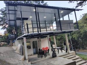 a house with a balcony with tables and chairs at Cabaña La Rivera in Macanal