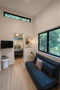 a living room with a blue couch and a window at Wave and Willow Tiny Home in Broughton Village