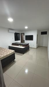 two beds in a large room with white tile floors at Temporadaemjaua in Camaçari