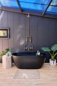 a black bath tub in a room with plants at Wave and Willow Tiny Home in Broughton Village +25 photos