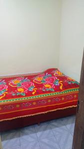 a bed with a red blanket with flowers on it at Oliveira Hospedagens in Salvador