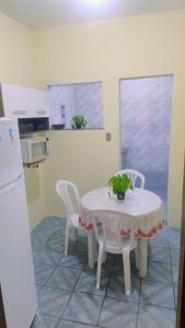 a kitchen with a table and two chairs and a white table and a refrigerator at Oliveira Hospedagens in Salvador
