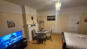 a room with a table and a bed and a television at The ultimate group stay in Catford