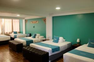 a room with three beds with blue walls at MATARA GREENS HOTEL in Cusco