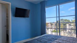 a bedroom with a blue wall with a flat screen tv at Henrietta Place B&B in Progreso