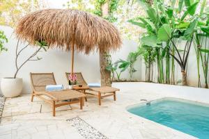 a patio with two chairs and an umbrella next to a swimming pool at Casa Myla Luxury Villa - Bingin in Badung