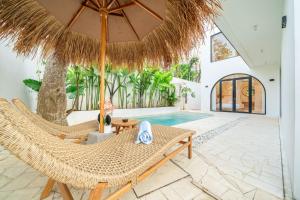 a villa with a pool and two chairs and an umbrella at Casa Myla Luxury Villa - Bingin in Badung