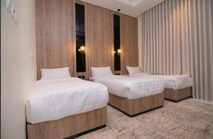 two beds in a room with wood walls at Princess House in Jeddah