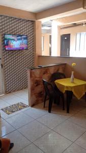 a dining room with a yellow table and chairs and a television at Pousada Vó Ana Reis in Aparecida