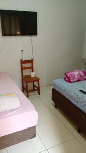 a bedroom with two beds and a chair and a flat screen tv at Pousada Vó Ana Reis in Aparecida
