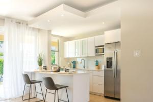 a kitchen with white cabinets and a counter with chairs at Solimar Villa Family Vacation Spot in Playa de Guayanes