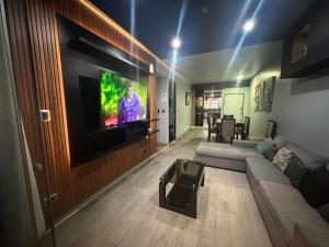 a living room with a couch and a tv on a wall at Miraflores Alcanfores in Lima