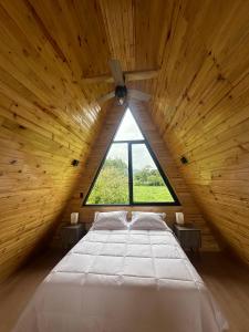 a large bed in a wooden room with a window at Villa Alpina in Oxapampa