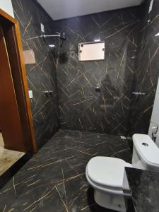 a bathroom with a toilet and a black marble wall at APART HOTEL Lar Doce Lar 2 & 7 in Arcos