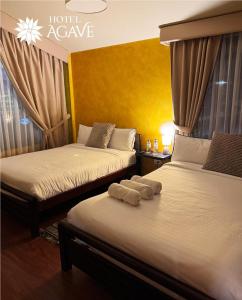 two beds in a hotel room with towels on them at Hotel Casa Agave in Baños