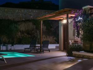 a patio with chairs and a swimming pool at night at Ano Mera Villa with Private Pool in Ano Mera