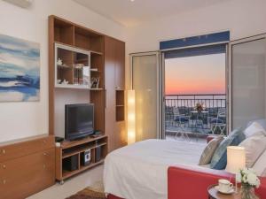 a bedroom with a bed and a tv and a balcony at Rhodes Retreat with Private Pool in Kalathos