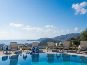 a pool with chairs and the ocean in the background at Rhodes Retreat with Private Pool in Kalathos