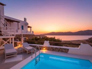 a villa with a swimming pool and a sunset at Panormos Retreat with Pool in Mikonos