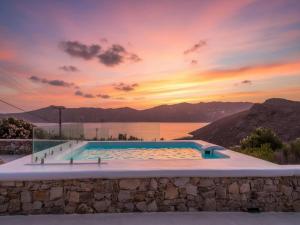 a swimming pool with a sunset in the background at Panormos Stay for Seven Guests in Mikonos