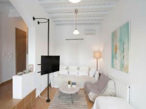 a white living room with a couch and a tv at 3-Bed Home in Ano Mera in Ano Mera
