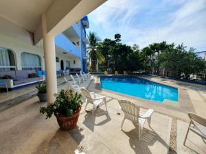 a swimming pool with white chairs and a house at Hotel Kootznoowoo in Puerto Escondido