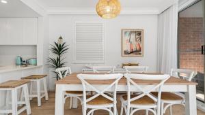 a dining room with a wooden table and white chairs at Sea Glass in Terrigal