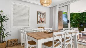 a dining room with a wooden table and white chairs at Sea Glass in Terrigal