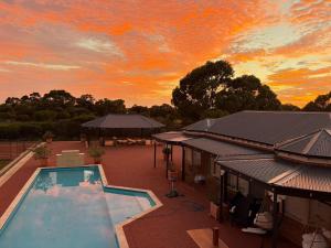 an outdoor swimming pool with a sunset in the background at Wonnerup Beach Manor in Wonnerup