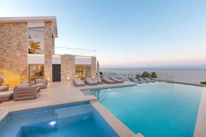 a villa with a swimming pool with chairs and the ocean at Kokkari Villa in Kokkari
