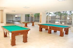 two pool tables in a large room with windows at Apartamento Veredas Flat - Rio Quente in Rio Quente