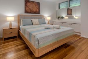 a large bed in a bedroom with two lamps at Poinciana 106 in Hamilton Island +7 photos