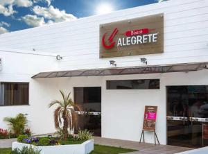 un edificio blanco con un signo agregado de albert en Hotel Alegrete, en Alegrete