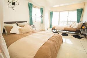 a bedroom with two beds and a large window at GUEST HOUSE SORA 2 in Okinawa City