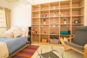 a bedroom with a bed and a chair and shelves at GUEST HOUSE SORA 2 in Okinawa City
