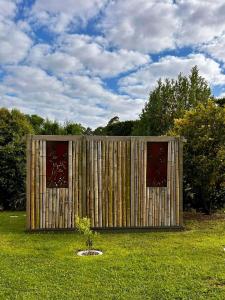 a small wooden building in a field of grass at Among The Tuii in Katikati