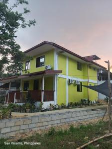 a yellow house with a fence in front of it at Kenji Guest House in San Vicente