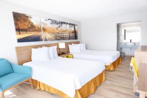 a hotel room with two beds and a blue chair at Days Inn by Wyndham Frankfort in Frankfort