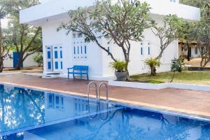 a villa with a swimming pool in front of a house at Blue Kite Retreat in Kalpitiya