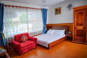a bedroom with a bed and a red chair at Diamond Suite Dai Nam Hotel in Can Tho